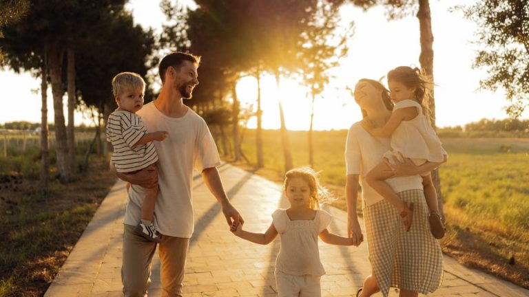 A joyful family walking together on a sunlit path during sunset, enjoying an outdoor stroll.